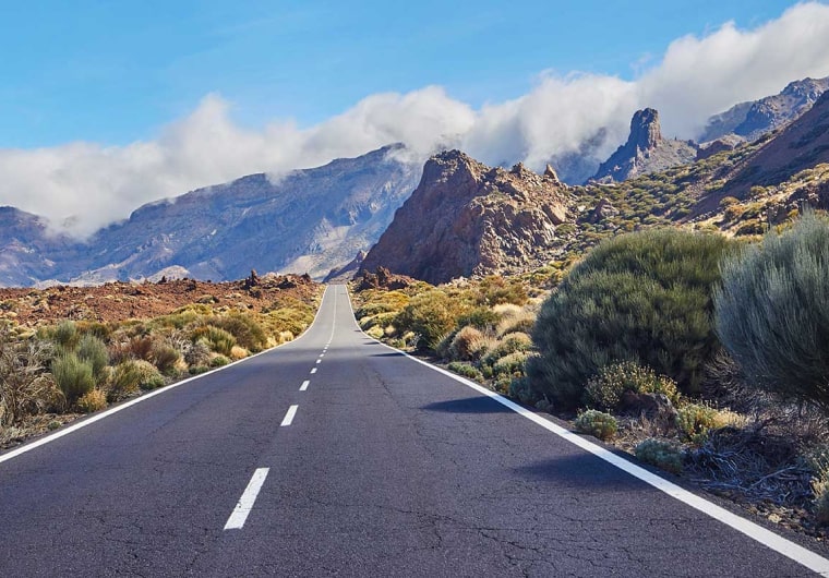 Photo of a road leading towards some mountains in the distance