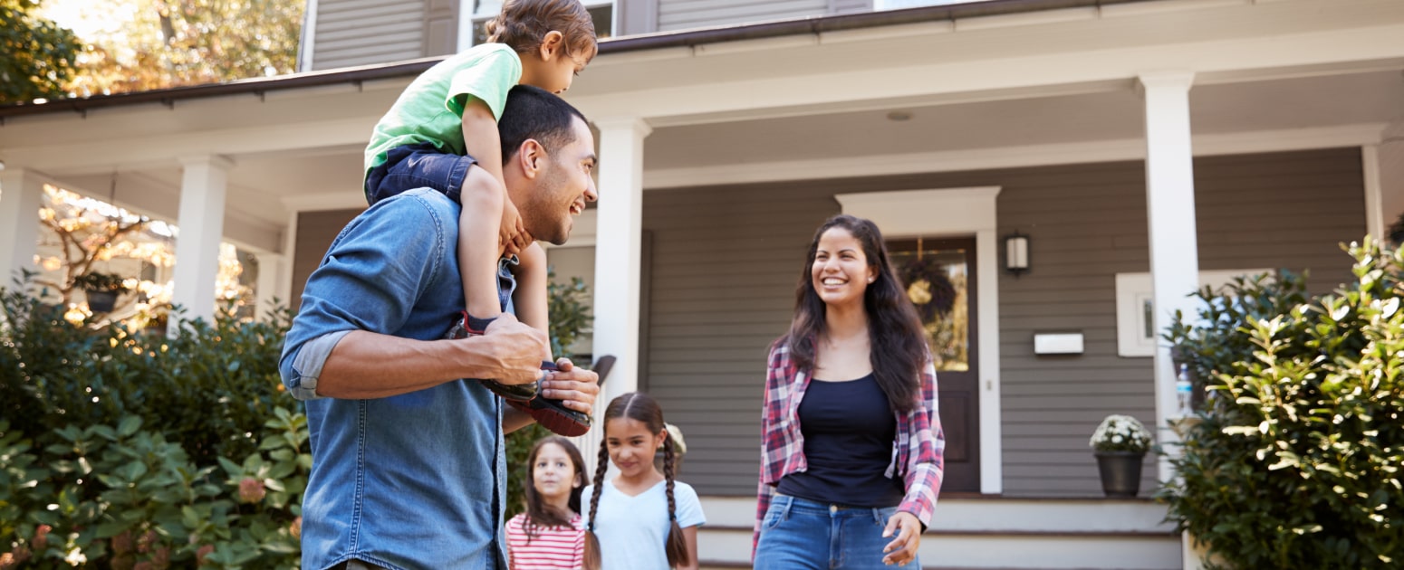 Photo of a family smiling walking away from a house